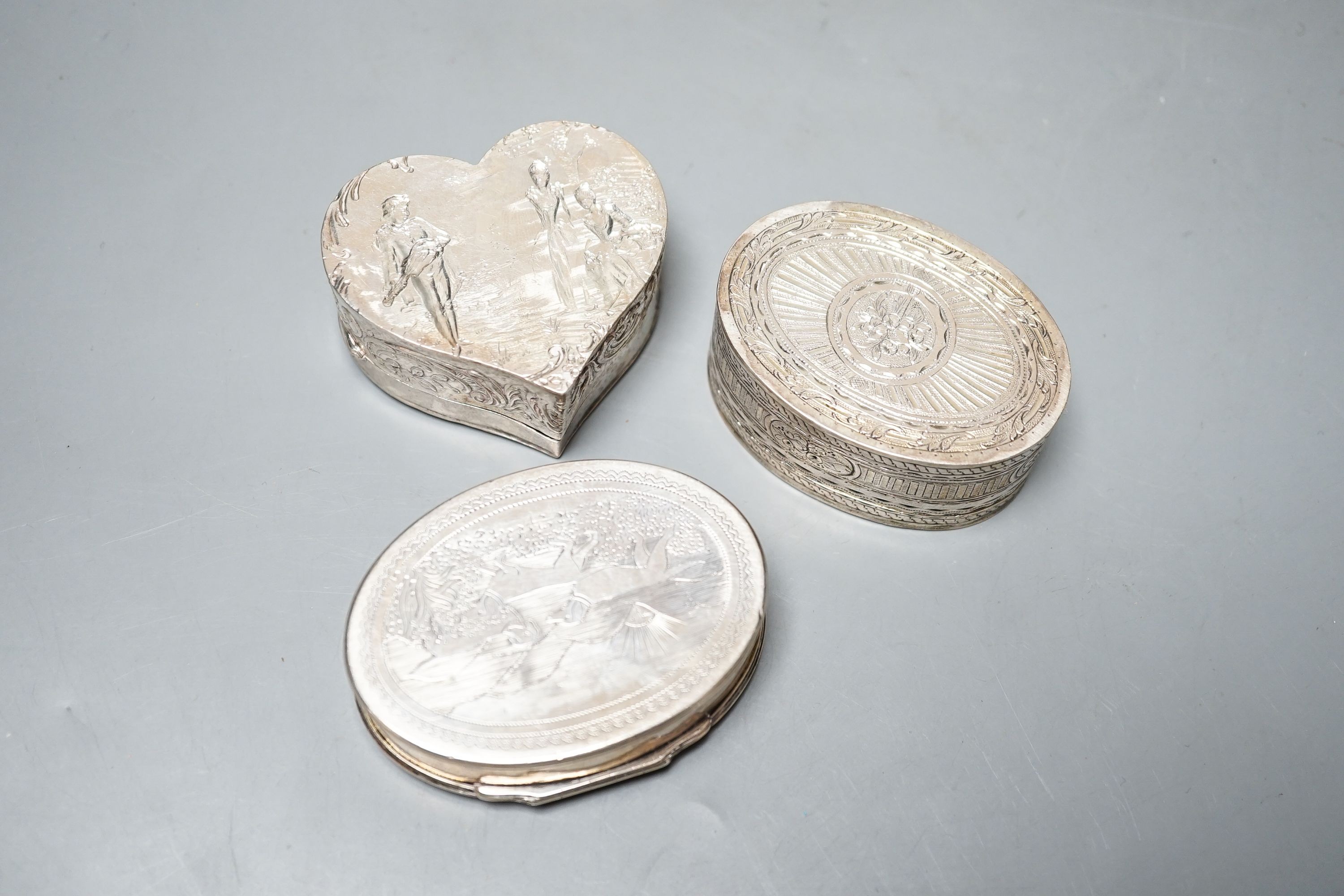 A continental oval white metal snuff box, engraved with hunting scenes, 72mm, a silver oval snuff box with Sheffield, import marks, a silver heart shaped box and a silver cigarette box.
